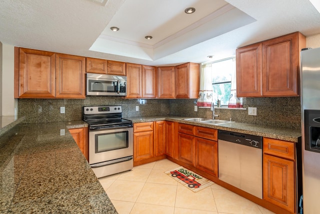 kitchen featuring appliances with stainless steel finishes, sink, backsplash, light tile patterned floors, and a tray ceiling