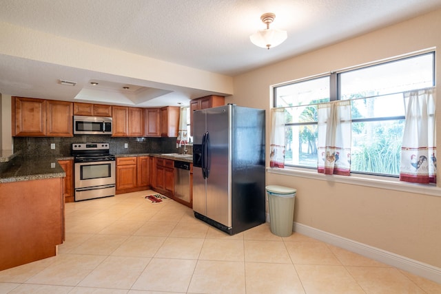 kitchen featuring sink, appliances with stainless steel finishes, light tile patterned flooring, decorative backsplash, and a raised ceiling