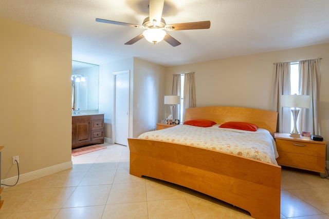 bedroom with ceiling fan, connected bathroom, a textured ceiling, and light tile patterned floors