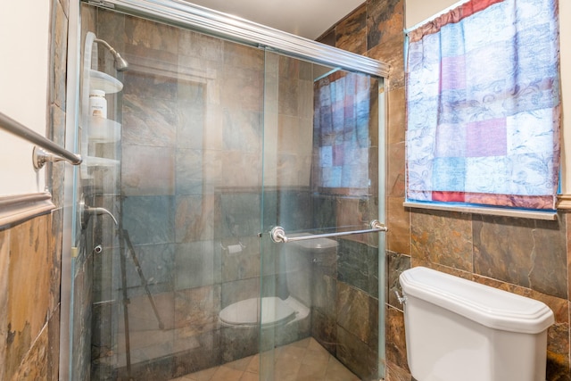 bathroom with tile walls, a shower with shower door, and toilet