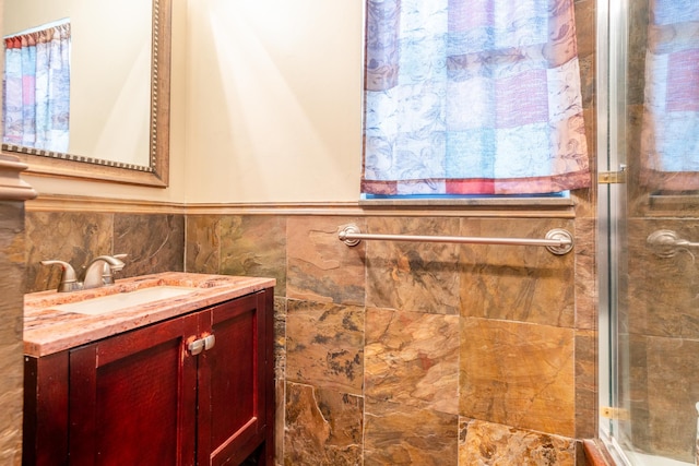 bathroom featuring vanity, a shower with door, and tile walls