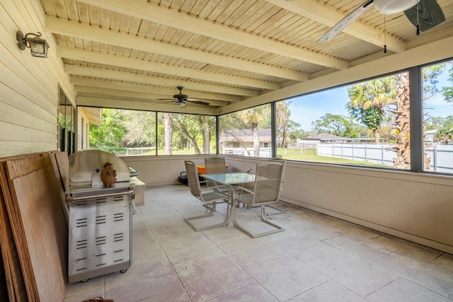 unfurnished sunroom with beamed ceiling, ceiling fan, a healthy amount of sunlight, and wooden ceiling