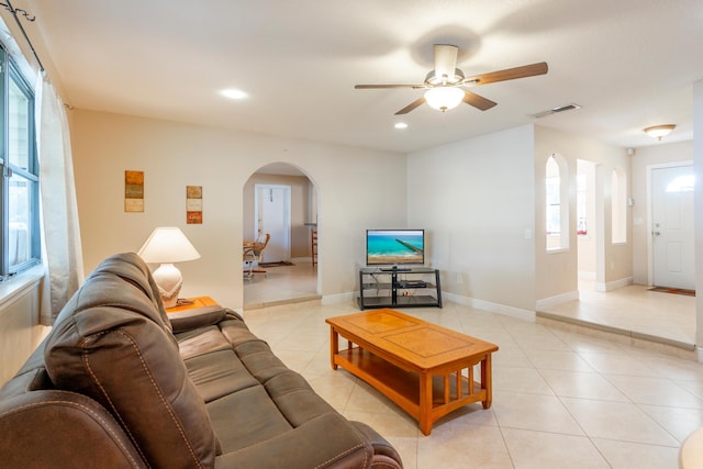 living room with a wealth of natural light, ceiling fan, and light tile patterned floors