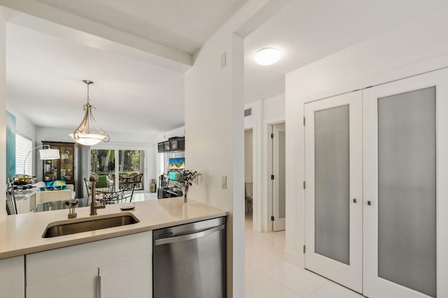 kitchen with white cabinets, light tile patterned floors, sink, stainless steel dishwasher, and decorative light fixtures