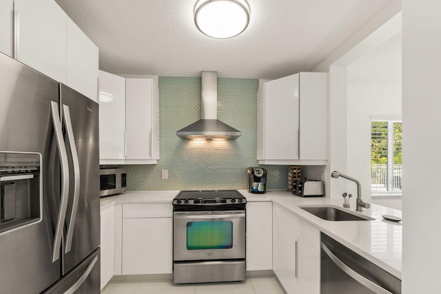 kitchen featuring white cabinets, sink, backsplash, wall chimney range hood, and stainless steel appliances