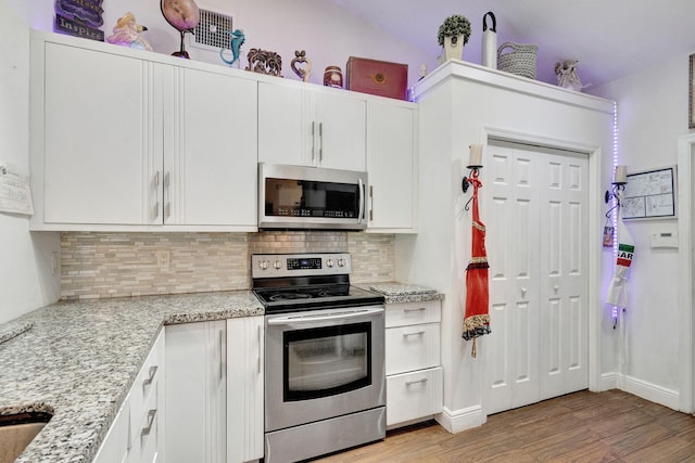 kitchen with white cabinets, stainless steel appliances, light hardwood / wood-style flooring, and light stone countertops