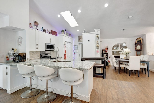 17891 N 86th St N, The Acreage, FL 33470 - kitchen featuring stainless steel appliances, a skylight, light wood-type flooring, a sink, and recessed lighting