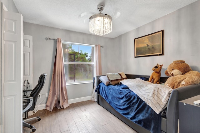 bedroom featuring wood-type flooring, a notable chandelier, and a textured ceiling