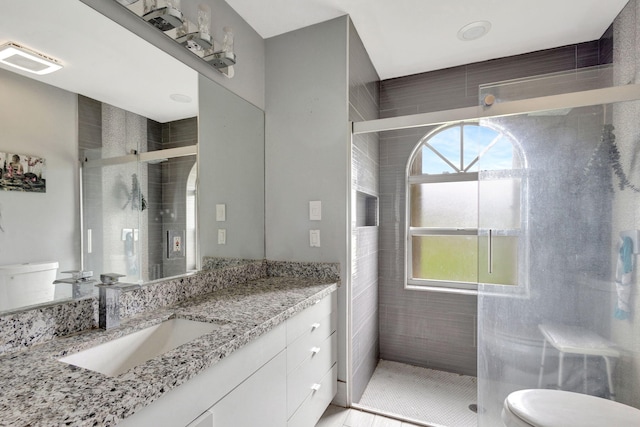 bathroom featuring tile patterned flooring, vanity, toilet, and a shower with shower door