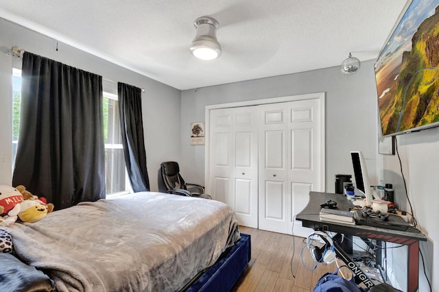 bedroom featuring a textured ceiling, hardwood / wood-style floors, ceiling fan, and a closet