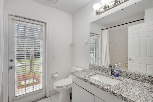 bathroom with toilet, a wealth of natural light, vanity, and tile patterned floors