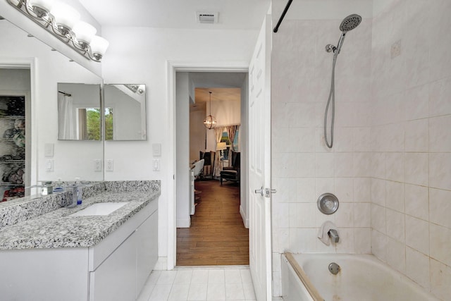 bathroom featuring tiled shower / bath, hardwood / wood-style flooring, and vanity