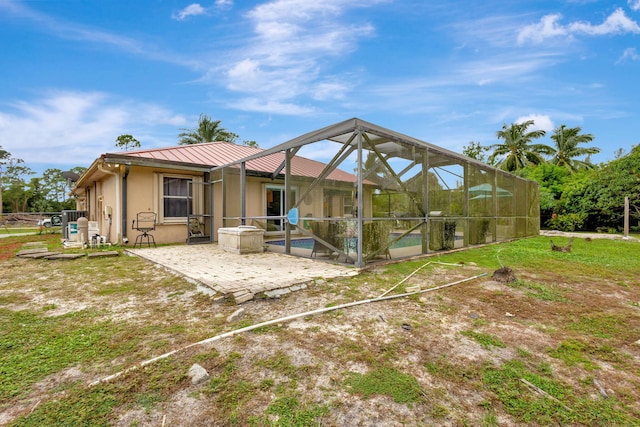 back of house with a swimming pool, glass enclosure, and a patio area