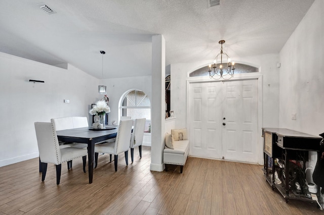 dining room with an inviting chandelier, hardwood / wood-style flooring, and a textured ceiling