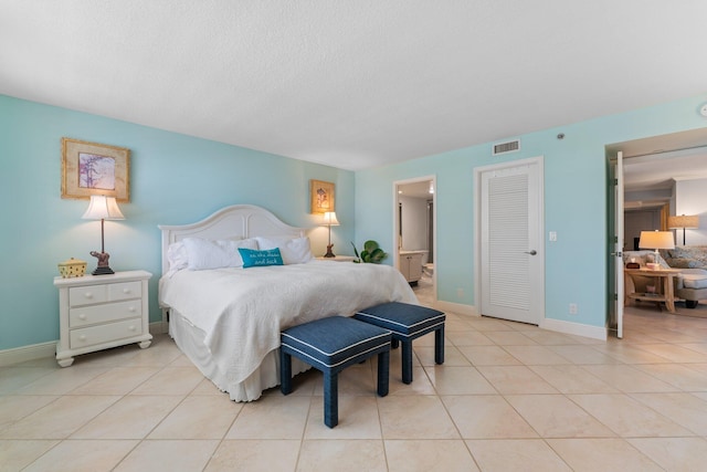 bedroom featuring ensuite bathroom and light tile floors