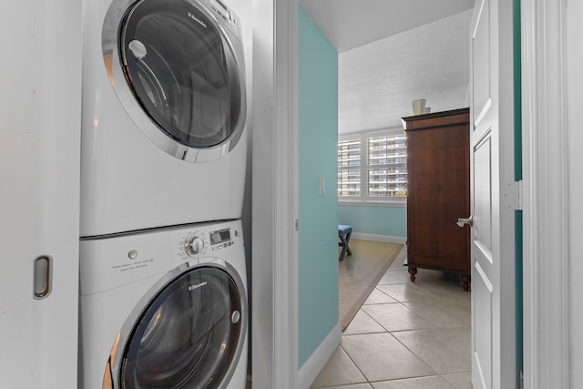 laundry area featuring stacked washer / dryer and light tile flooring