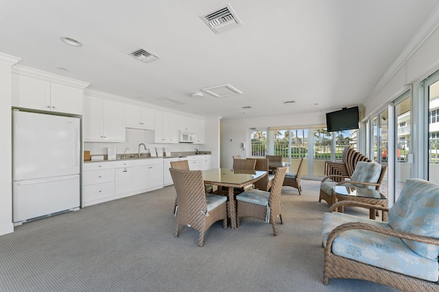 dining space featuring light carpet, sink, and ornamental molding