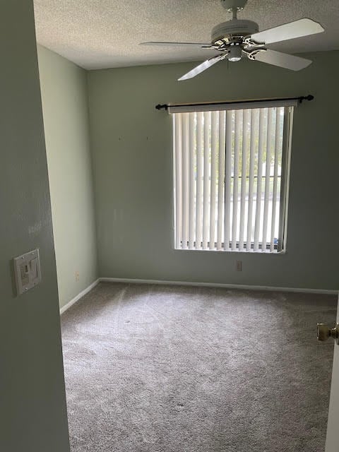 carpeted empty room featuring ceiling fan and a textured ceiling