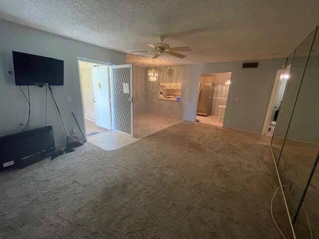 unfurnished living room with ceiling fan, a textured ceiling, and light carpet