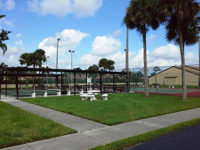 view of home's community featuring tennis court and a lawn