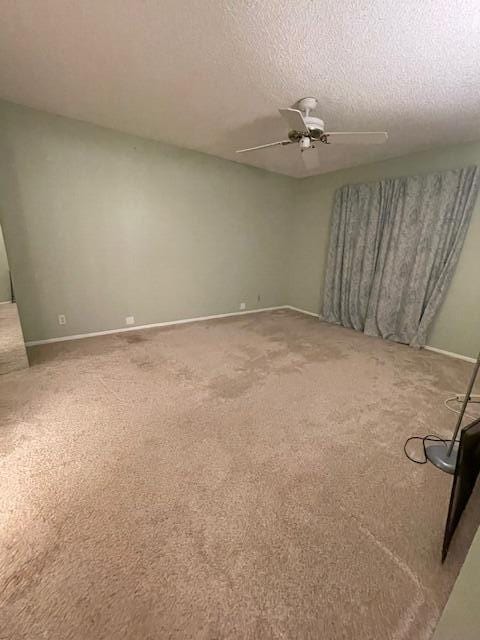 carpeted spare room with a textured ceiling and ceiling fan