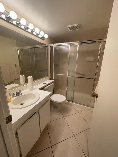 bathroom with tile patterned floors, vanity, a shower with door, and toilet