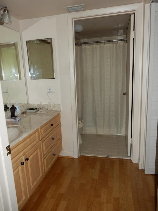 bathroom with hardwood / wood-style flooring, toilet, and vanity