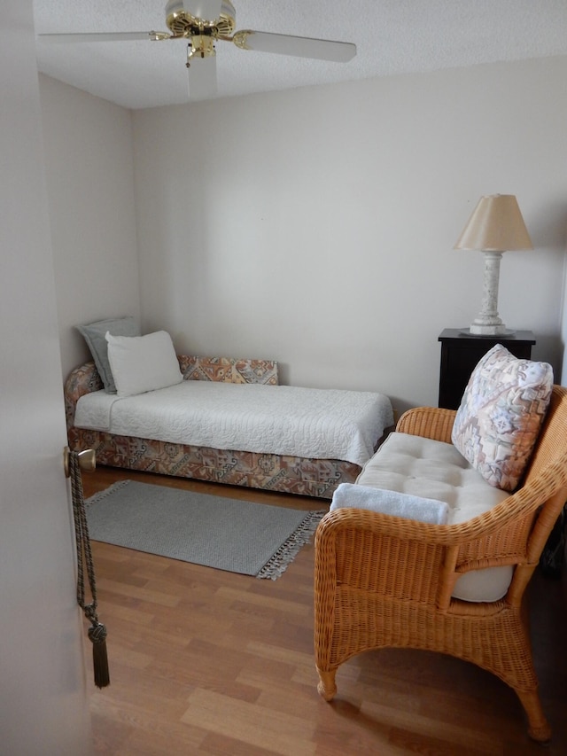 bedroom with light hardwood / wood-style floors, ceiling fan, and a textured ceiling