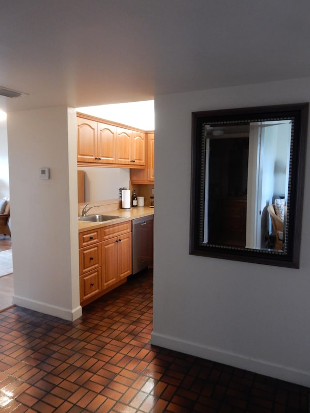 kitchen featuring light brown cabinetry, sink, and dishwasher