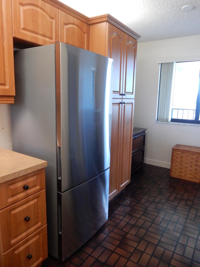 kitchen featuring stainless steel fridge and a textured ceiling