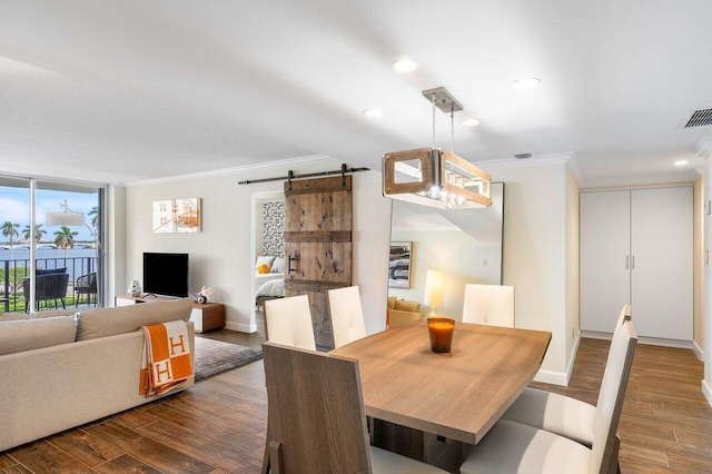 dining room with a barn door, ornamental molding, and dark hardwood / wood-style flooring