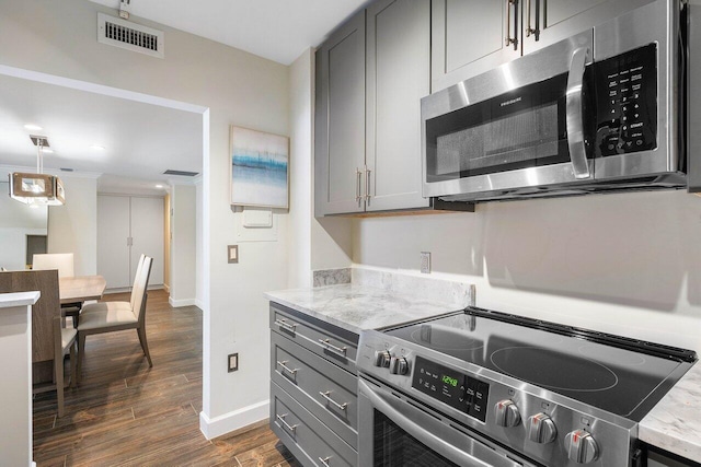 kitchen featuring dark hardwood / wood-style floors, gray cabinetry, appliances with stainless steel finishes, light stone countertops, and decorative light fixtures