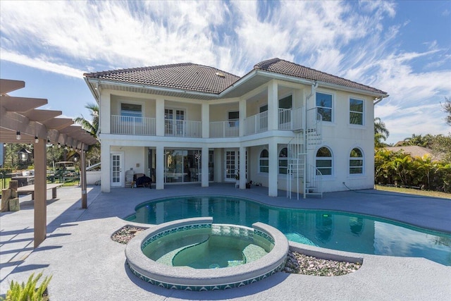 back of property featuring a swimming pool with hot tub, a pergola, a patio, and a balcony