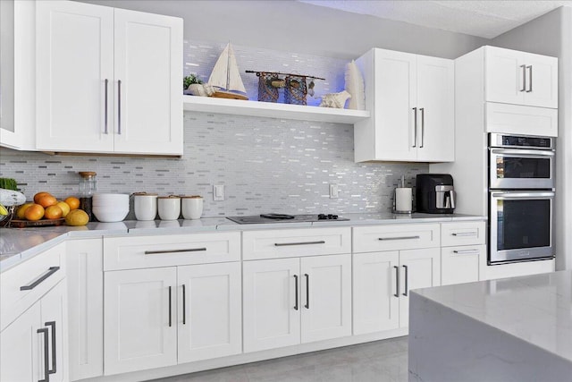 kitchen featuring light stone countertops, tasteful backsplash, stainless steel appliances, and white cabinetry