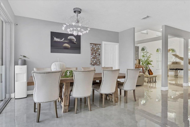 tiled dining space featuring an inviting chandelier and a textured ceiling