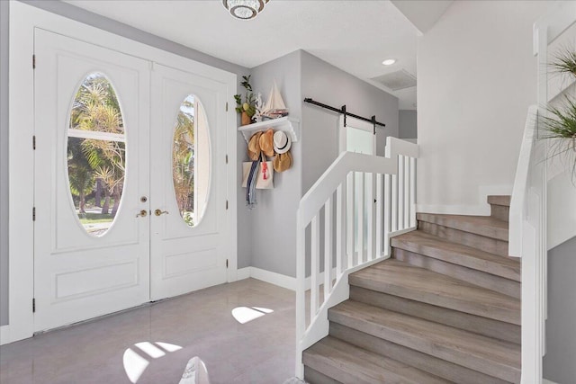 tiled foyer entrance featuring a barn door and french doors