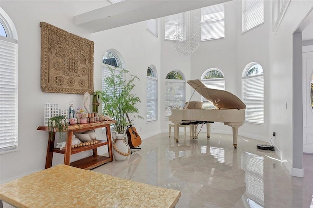 miscellaneous room featuring light tile flooring, a chandelier, and a towering ceiling