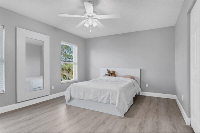 bedroom with ceiling fan, light hardwood / wood-style flooring, and a textured ceiling