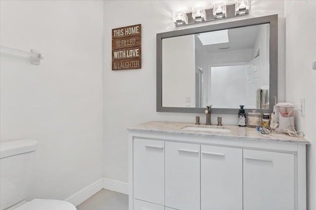 bathroom with toilet, a skylight, and vanity with extensive cabinet space