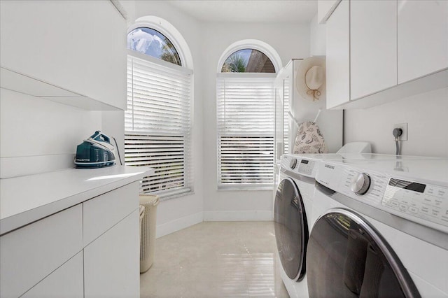 washroom featuring light tile flooring, electric dryer hookup, separate washer and dryer, and cabinets