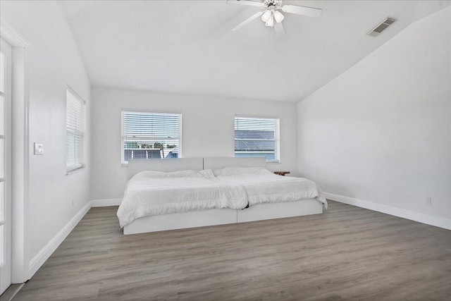 bedroom with hardwood / wood-style floors, multiple windows, ceiling fan, and vaulted ceiling