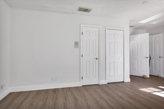 unfurnished bedroom with dark wood-type flooring and a textured ceiling