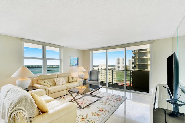 living room with light tile floors, a textured ceiling, a healthy amount of sunlight, and a water view