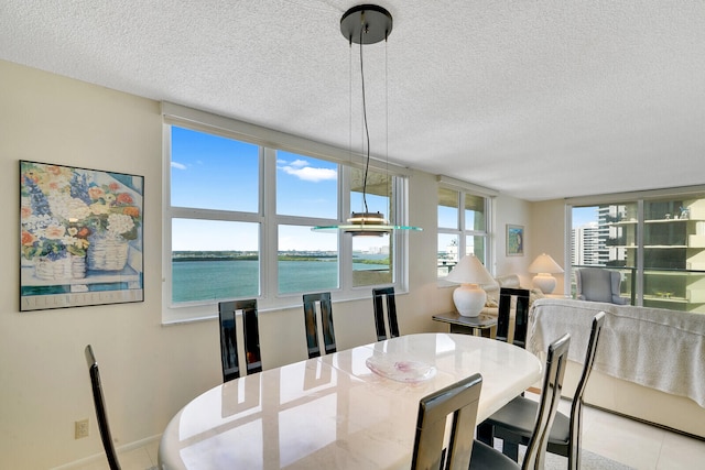 dining space featuring light tile floors, a textured ceiling, and a water view