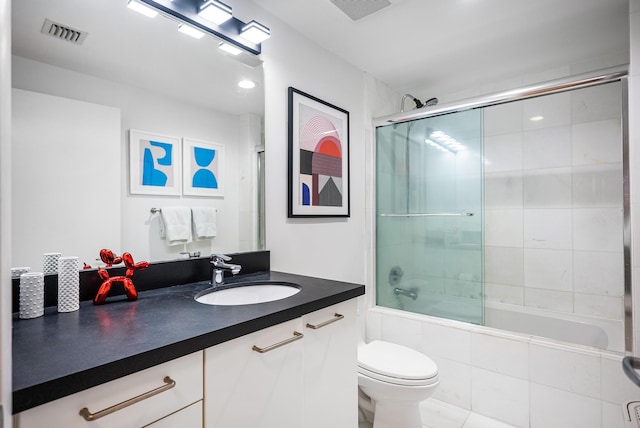 full bathroom featuring tile patterned flooring, vanity, toilet, and shower / bath combination with glass door