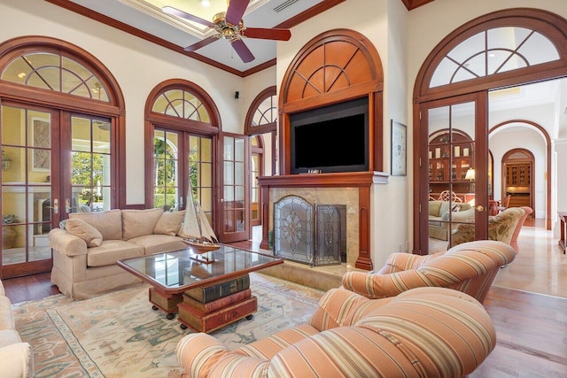 living room with a premium fireplace, crown molding, wood-type flooring, and ceiling fan