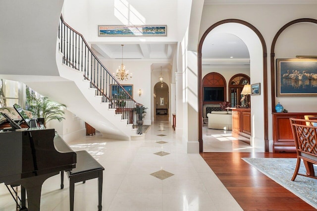 tiled foyer entrance featuring a chandelier, a towering ceiling, and crown molding