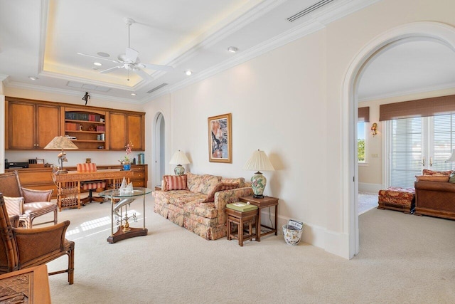 carpeted living room with crown molding, ceiling fan, and a tray ceiling