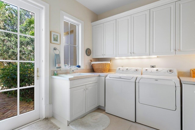 laundry area featuring washer and dryer, light tile floors, cabinets, and sink