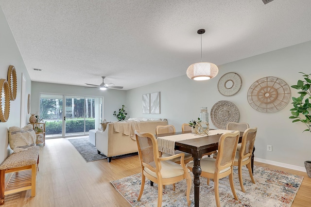 dining room featuring a textured ceiling, light hardwood / wood-style flooring, and ceiling fan